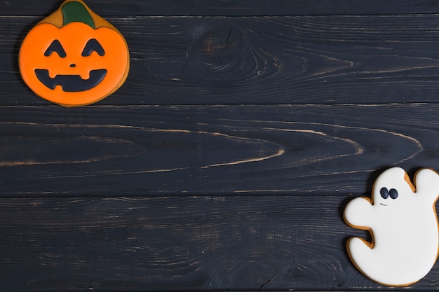 Zucca di Halloween e biscotti del fantasma sullo scrittorio di legno