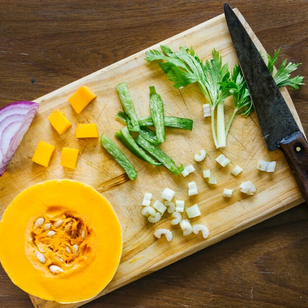 Zucca fresca; sedano e cipolla sul tagliere di legno