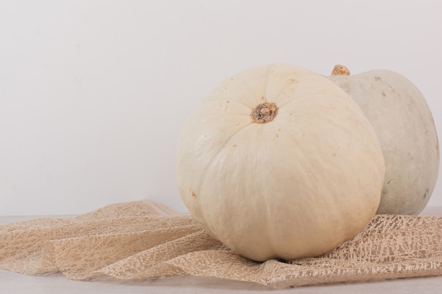 Zucca matura bianca su bianco con tela da imballaggio.