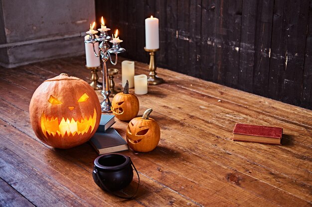 Zucche e candele spaventose su un pavimento di legno in una vecchia casa. Concetto di Halloween.