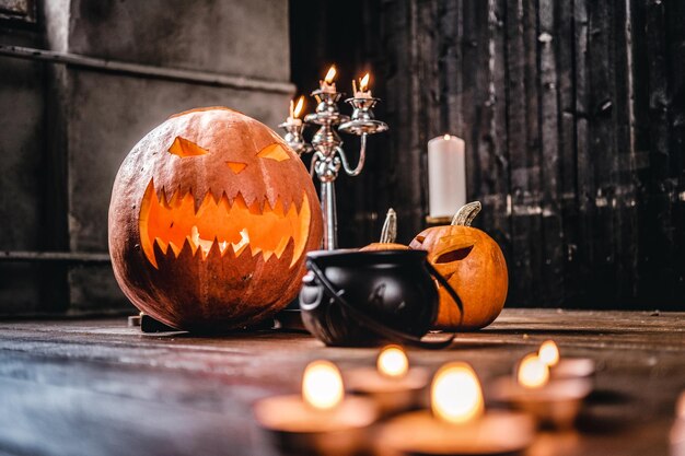 Zucche e candele spaventose su un pavimento di legno in una vecchia casa. Concetto di Halloween.