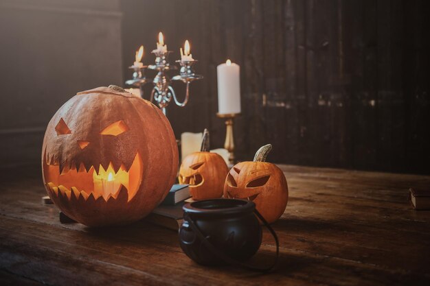 Zucche intagliate tradizionali di Halloween, piccola caldaia e candele sul pavimento di legno.