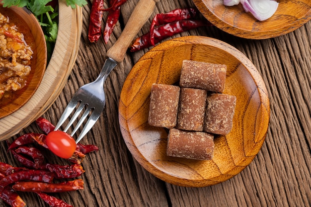 Zucchero di palma, cipolle rosse, peperoni secchi, pomodori, cetrioli, fagioli lunghi e lattuga in una ciotola.