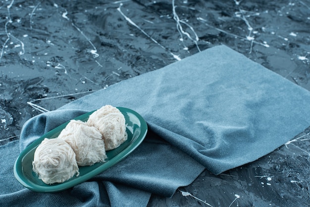 Zucchero filato turco tradizionale su un piatto su un asciugamano, sul tavolo blu.
