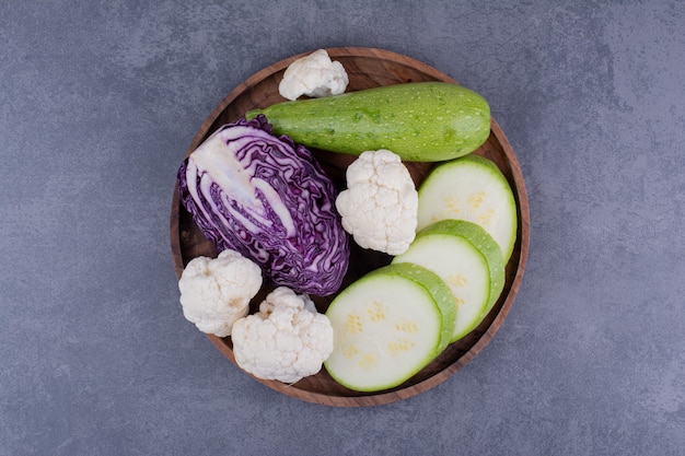 Zucchine a fette, cavolo viola e cavolfiori su un piatto di legno.