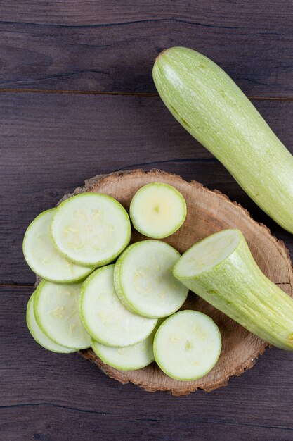 zucchine a fette sul troncone e tavolo in legno scuro.