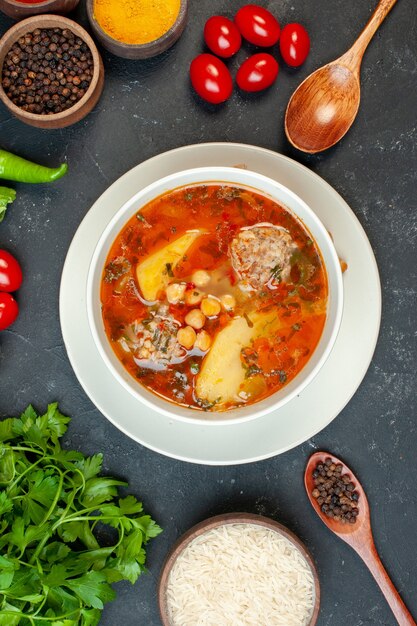 Zuppa di carne gustosa vista dall'alto con verdure e condimenti su sfondo scuro