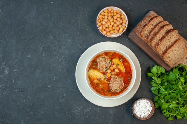 Zuppa di carne vista dall'alto con pagnotte di pane su uno sfondo grigio scuro