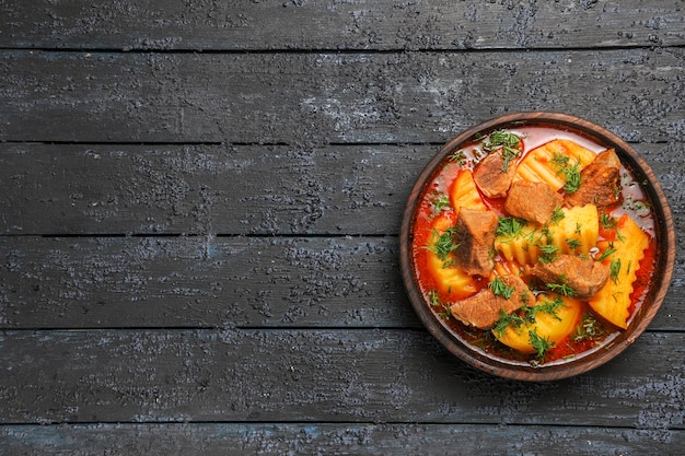 Zuppa di carne vista dall'alto con patate e verdure sul pavimento scuro