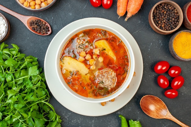 Zuppa di carne vista dall'alto con verdure e condimenti su sfondo scuro