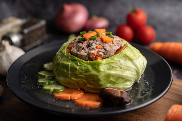 Zuppa di cavolo cappuccio di maiale con carote, cipolle verdi tritate, cetriolo in un piatto di legno su un piatto di legno