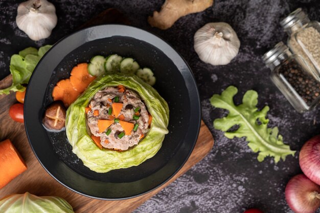 Zuppa di cavolo cappuccio di maiale con carote, cipolle verdi tritate, cetriolo in un piatto di legno su un piatto di legno