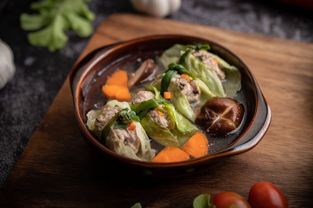 Zuppa di cavolo cappuccio di maiale con carote, cipolle verdi tritate, cetriolo in un piatto di legno su un piatto di legno