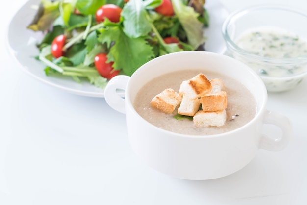 Zuppa di funghi e pane in tazza di ceramica bianca