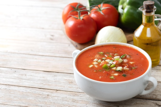 Zuppa di gazpacho spagnolo tradizionale in ciotola su tablexA di legno