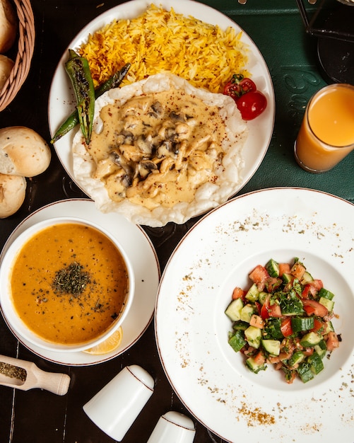 Zuppa di lenticchie di primo e secondo piatto con vista dall'alto con insalata greca e piatto principale e succo di frutta sul tavolo