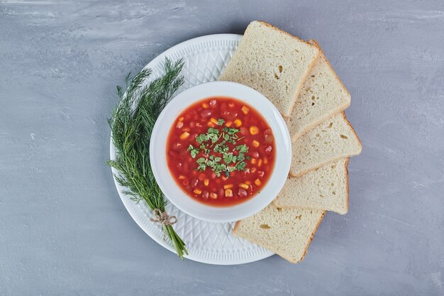 Zuppa di mais in salsa di pomodoro in un piatto bianco con erbe aromatiche.