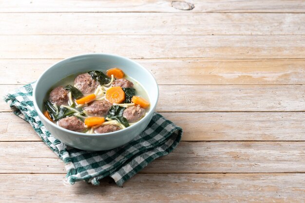 Zuppa di nozze italiana con polpette e spinaci su un tavolo di legno.