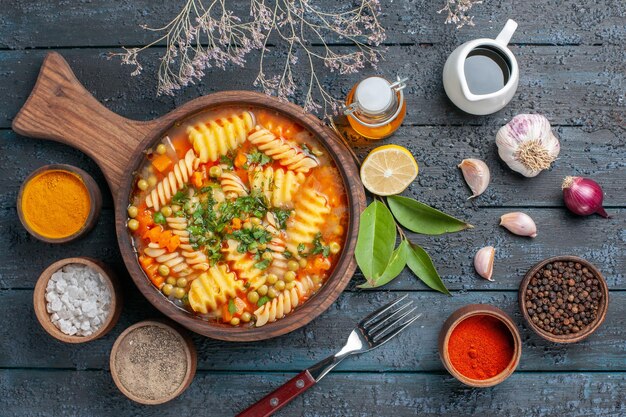 Zuppa di pasta a spirale vista dall'alto con condimenti sul piatto di cucina di pasta italiana colore salsa di zuppa da scrivania blu scuro