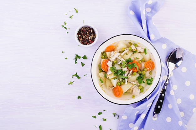 Zuppa di pollo con piselli, carote e patate in una ciotola bianca