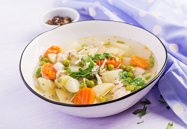 Zuppa di pollo con piselli, carote e patate in una ciotola bianca