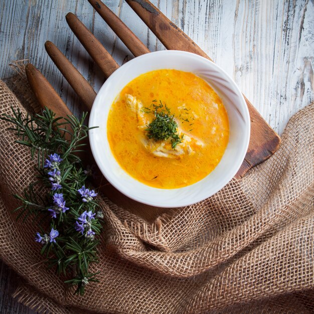 Zuppa di pollo vista dall'alto con foglie di rosmarino e verdure a bordo di cibo