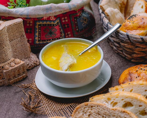 Zuppa di pollo vista laterale in una ciotola con coscia di pollo e reggiseno sul tavolo