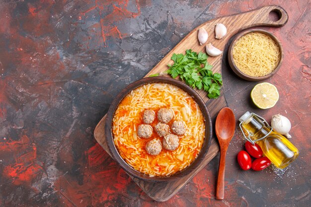 Zuppa di polpette con tagliatelle a bordo pasta cruda verdure al limone olio bottiglia e cucchiaio sul tavolo scuro