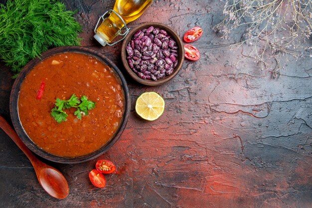 Zuppa di pomodoro classica in una ciotola marrone fagioli e cucchiaio una bottiglia di olio sulla tavola di colore misto