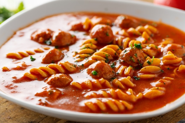 Zuppa di pomodoro italiana con pasta e polpette di carne servite sul piatto.