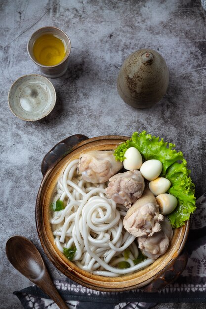 Zuppa di stile asiatico con noodles, carne di maiale e cipolle verdi da vicino in una ciotola sul tavolo.