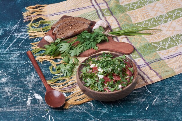 Zuppa di verdure in una tazza di legno con pane scuro.