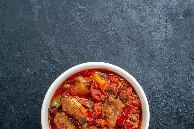 Zuppa di verdure vista dall'alto con carne all'interno del piatto su grigio scuro