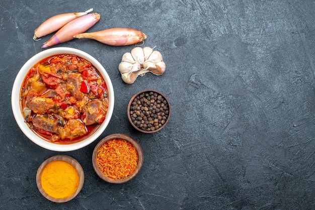 Zuppa di verdure vista dall'alto con carne e condimenti su grigio