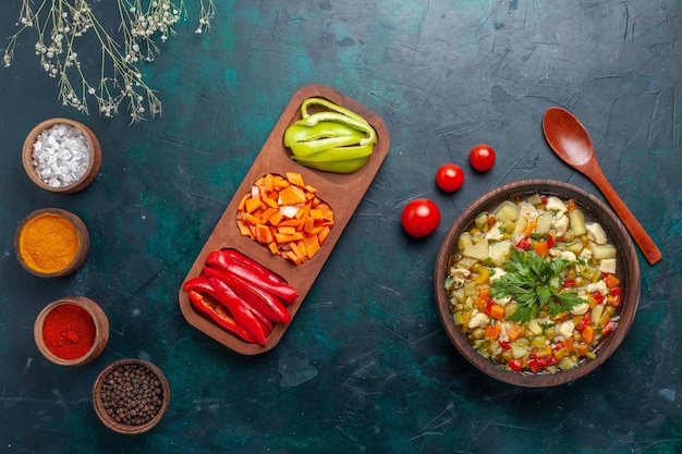 Zuppa di verdure vista dall'alto con diversi condimenti su sfondo blu scuro