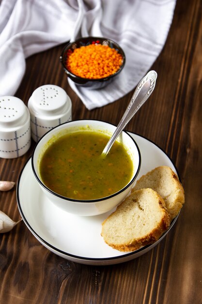 Zuppa di vista laterale con lenticchie con fette di pane con sale e pepe