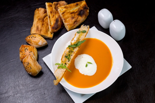 Zuppa di zucca con schiuma di latte focacce crackers rucola vista dall'alto