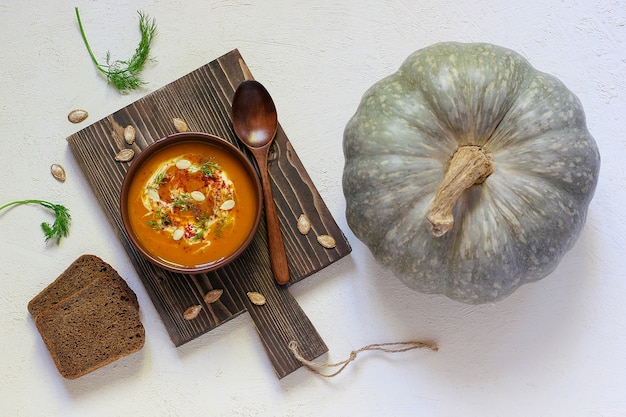 Zuppa di zucca e carote arrosto con crema, pepe nero e semi di zucca, tagliere e fette di zucca fresche, pane nero