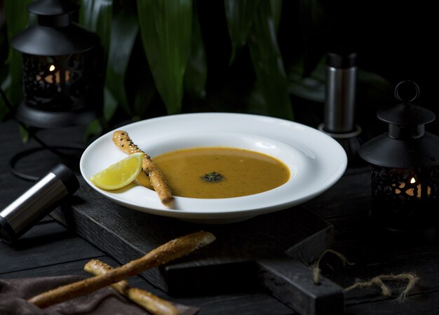 Zuppa di zucca in brodo di pollo con bastoncini di cannella e fette di limone