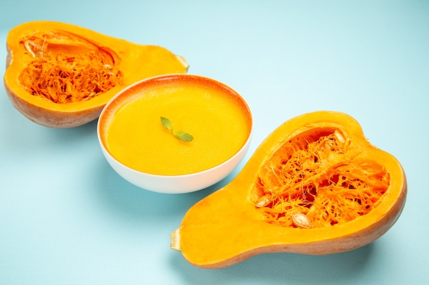 Zuppa di zucca vista frontale con zucche fresche sulla zuppa di colore piatto tavolo blu