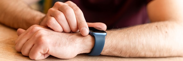 02232022 Mosca mano maschile con polso smart apple guardare i giovani che utilizzano la tecnologia moderna regolando e impostando l'ora sull'orologio toccando lo schermo digitale con il banner delle dita