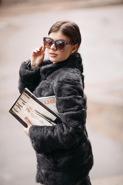 03 18 2019 Bielorussia Minsk Donna alla moda in pelliccia e occhiali da sole in posa per strada