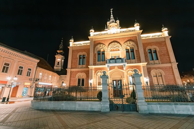 04 gennaio 2024 Novi Sad Serbia bellezza incantevole di Novi Sads Palazzo dei Vescovi illuminato contro il cielo del crepuscolo un notevole punto di riferimento architettonico