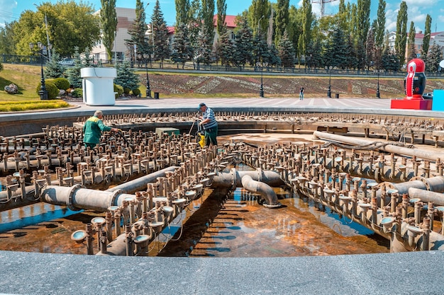09 giugno 2021 Ufa Russia Due operai puliscono e mantengono la vecchia fontana nel parco cittadino sulla piazza