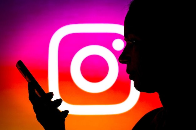 14 marzo 2022 Brasile In questa illustrazione fotografica il logo di Instagram visto sullo sfondo di una donna silhouette che tiene un telefono cellulare