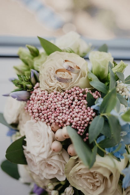 2 anelli d'oro sul bouquet da sposa con bellissime rose