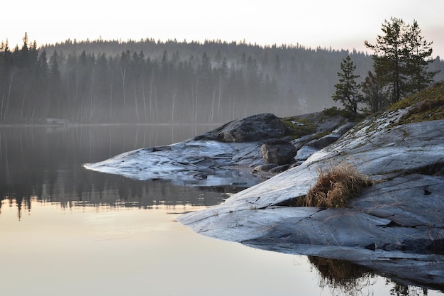 2 cappe di pietra un lago senza vento sullo sfondo una foresta nella nebbia riflessa nell'acqua