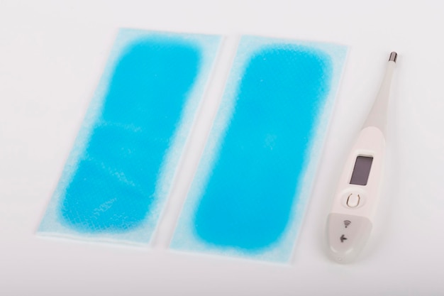 2 di fresco pad febbre e termometro digitale medico su sfondo bianco il pad febbre è una sensazione di raffreddamento istantaneo che calma il disagio della febbre strumenti medici di base