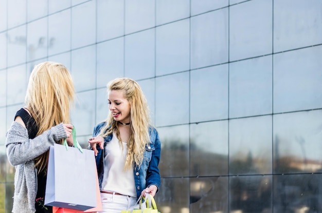 2 due amiche che fanno shopping con le borse al centro commerciale all'aperto