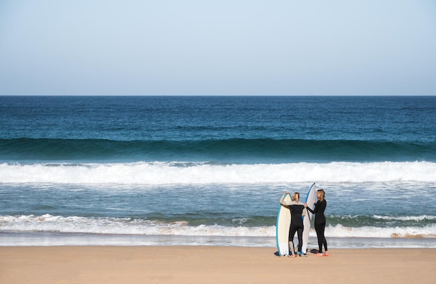 2 femmine sufer in piedi sulla spiaggia con le loro tavole da surf